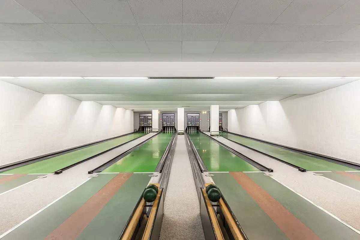 Interior of a bowling alley with vibrant green lanes and flooring for an immersive experience.