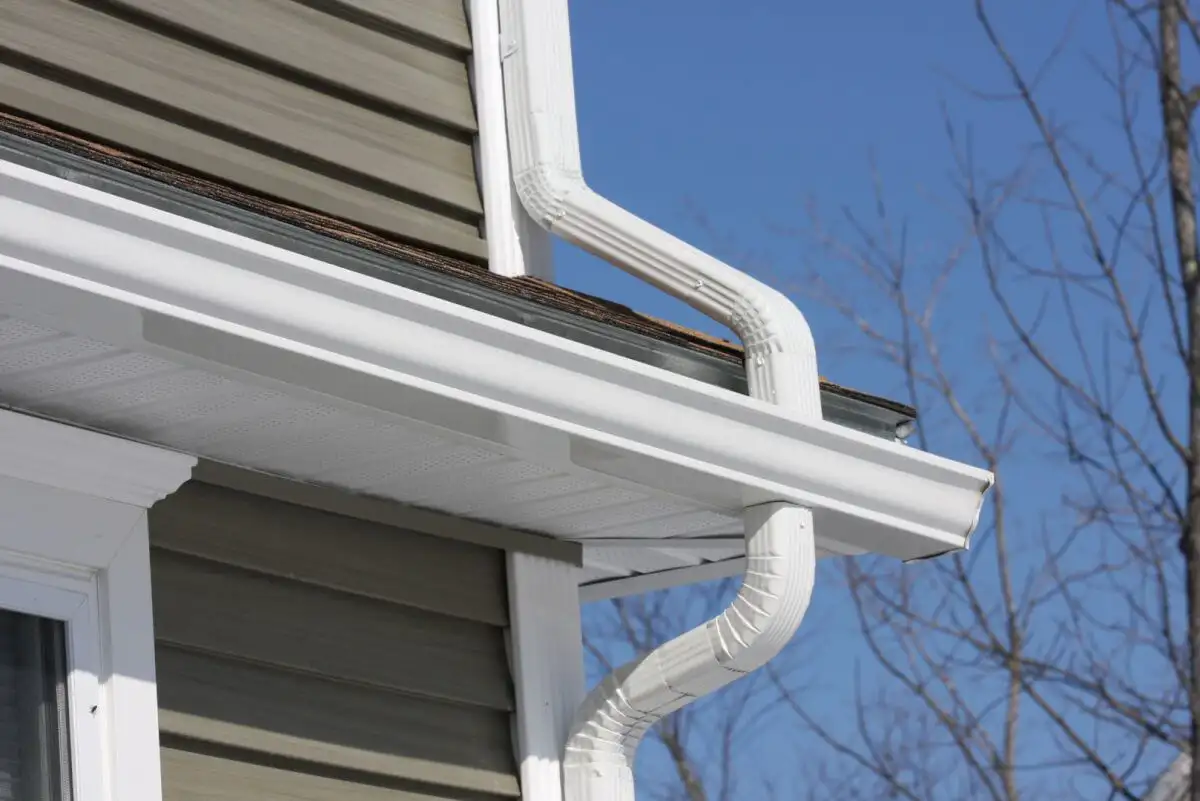 Close-up of a white gutter system and downspouts, illustrating gutter installation cost.